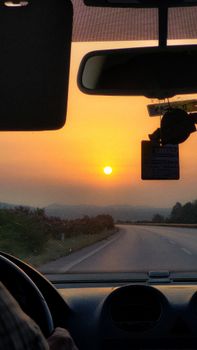 A scenic drive through a countryside road during sunset, viewed from a car's interior.