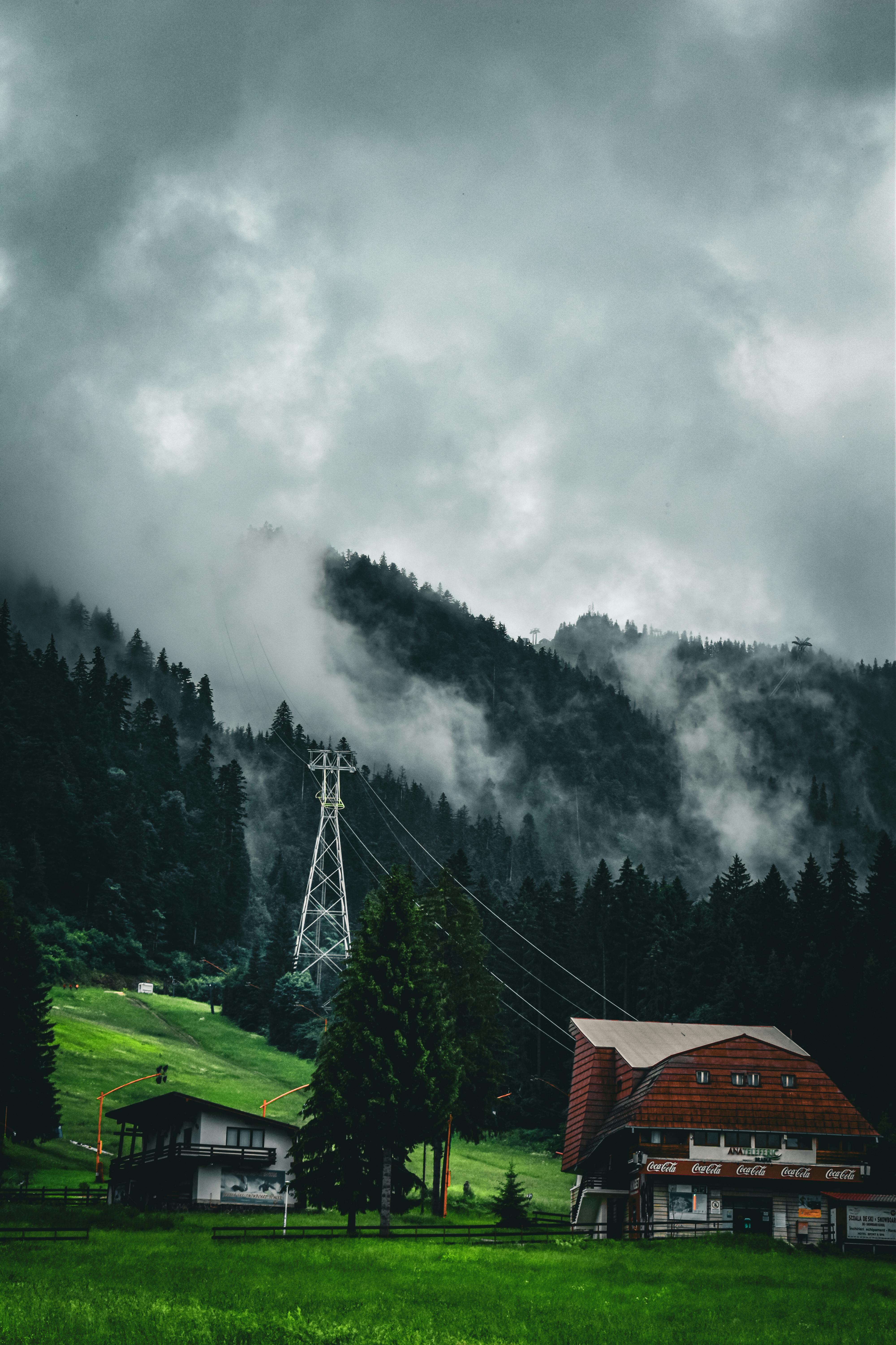 village under forest on hill under rain clouds