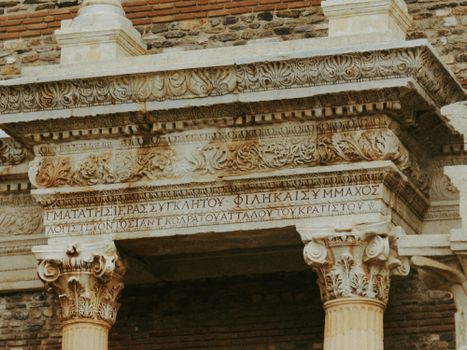Intricate stone carvings on an ancient Greek temple facade with Greek inscriptions.
