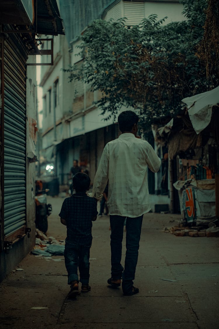 Man With Child Walking On Dirty Street