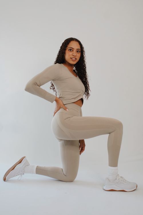 Free Confident woman posing in beige sportswear, showcasing modern fashion and style in a studio setting. Stock Photo