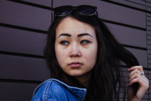 Young Woman in Sunglasses Posing near Wall