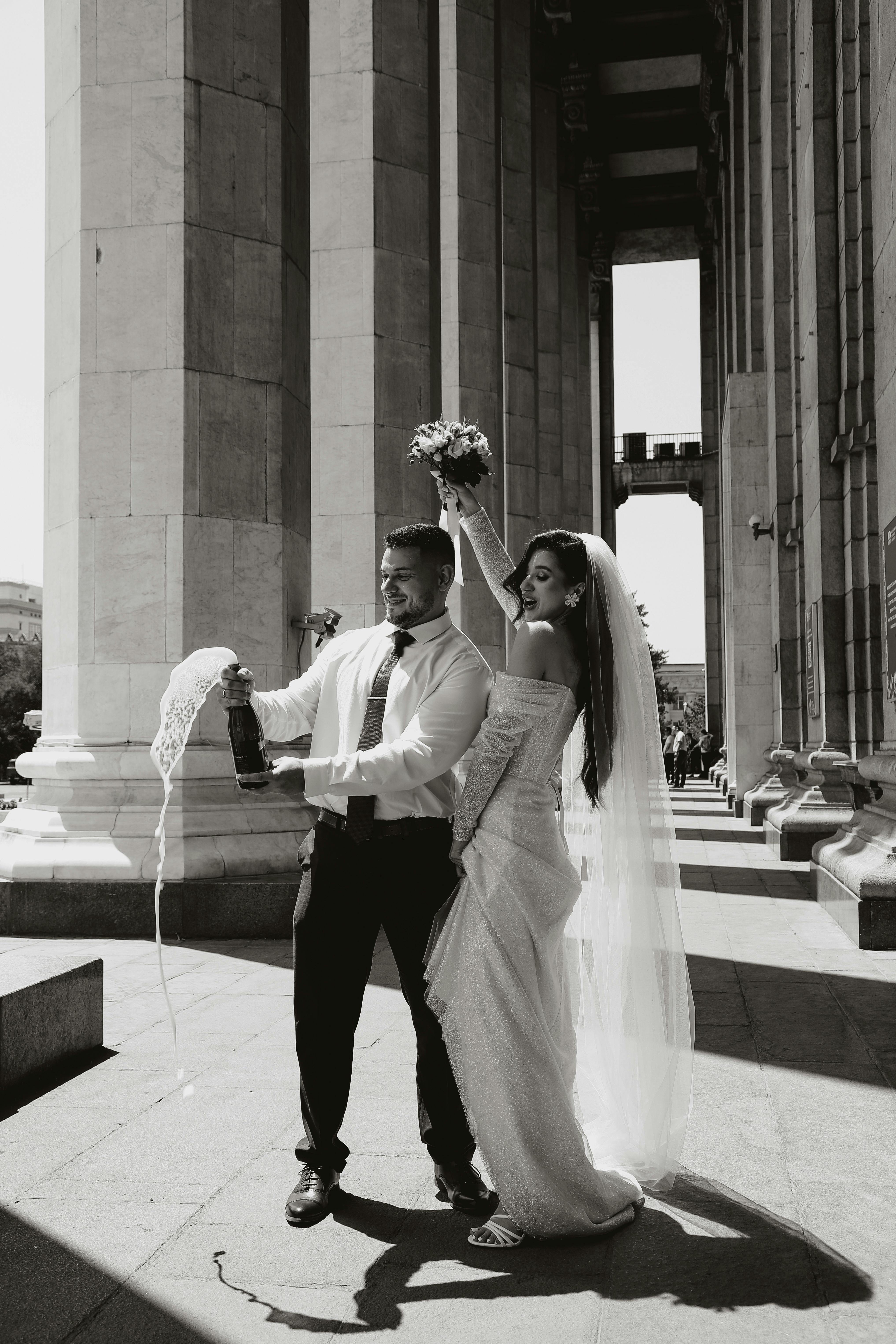 a newlywed couple opening a bottle of champagne