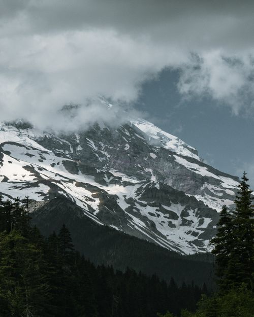 Free A stunning view of Mount Rainier with snow, clouds, and alpine trees in a winter landscape. Stock Photo