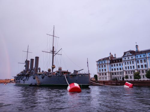 Free A historic warship anchored in a city harbor beside classic architecture. Stock Photo