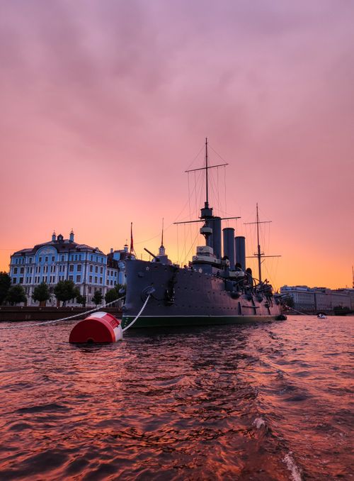 Free An anchored battleship in the harbor during a stunning sunset, creating a dramatic scene. Stock Photo
