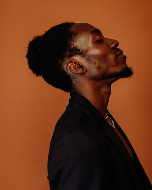 Profile Studio Shoot of a Man Posing against Orange Brown Background