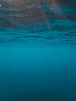 Tranquil underwater view of ocean waves with sunlight filtering through the water surface.
