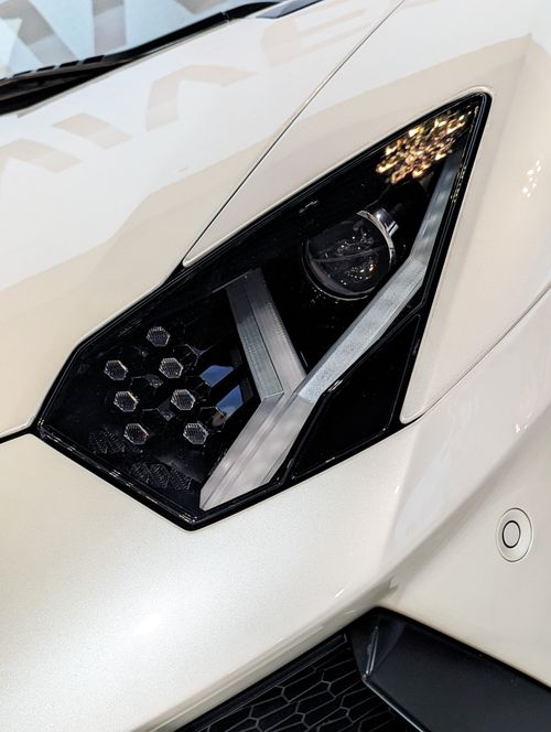 Free Detailed close-up of a white luxury sports car headlight in daylight. Stock Photo