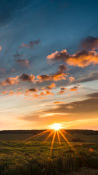 A stunning sunrise with sunbeams illuminating a picturesque countryside, enhancing the warm and peaceful atmosphere.