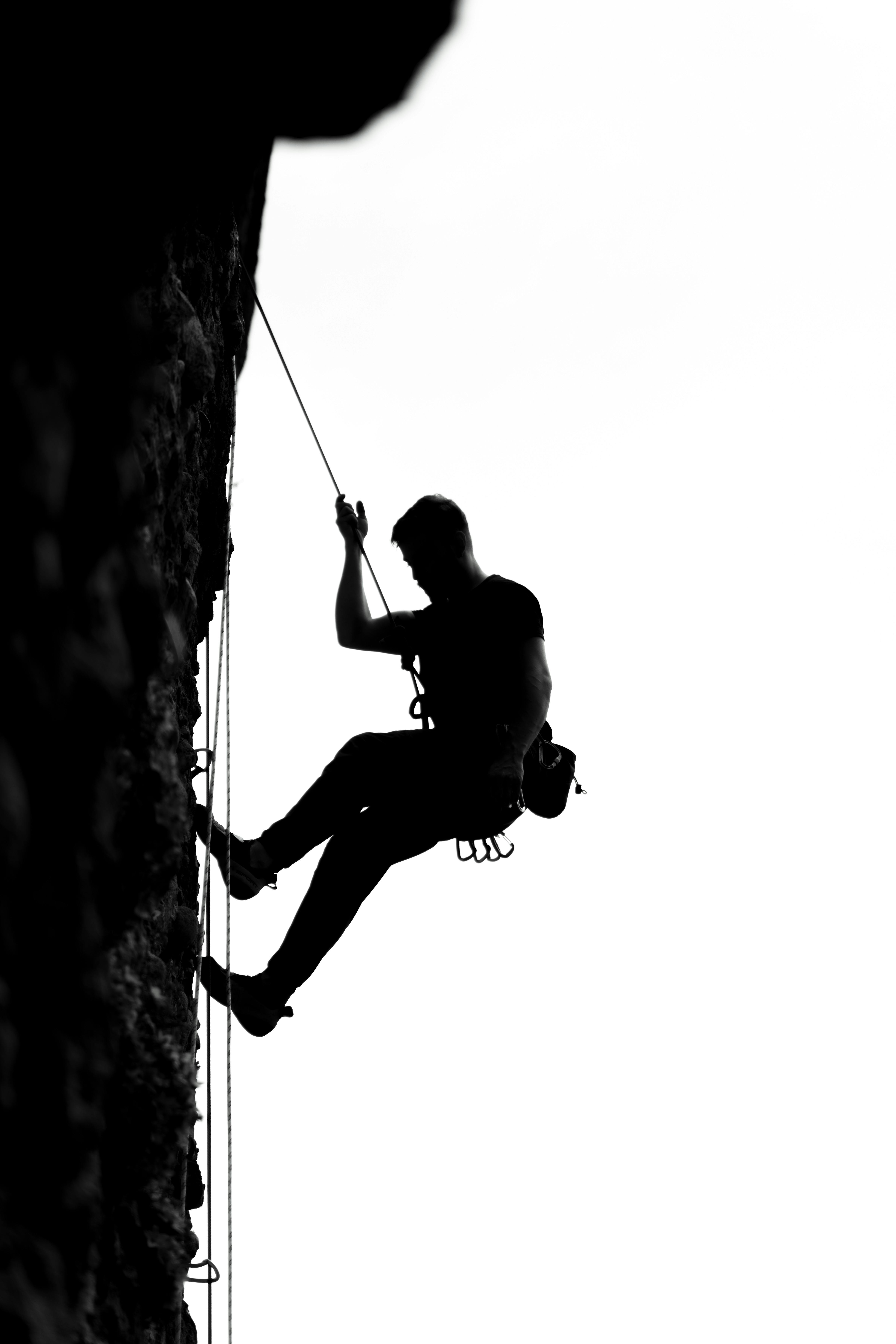 Black and white silhouette of a rock climber scaling a cliff in Pennadomo, Abruzzo, Italy.