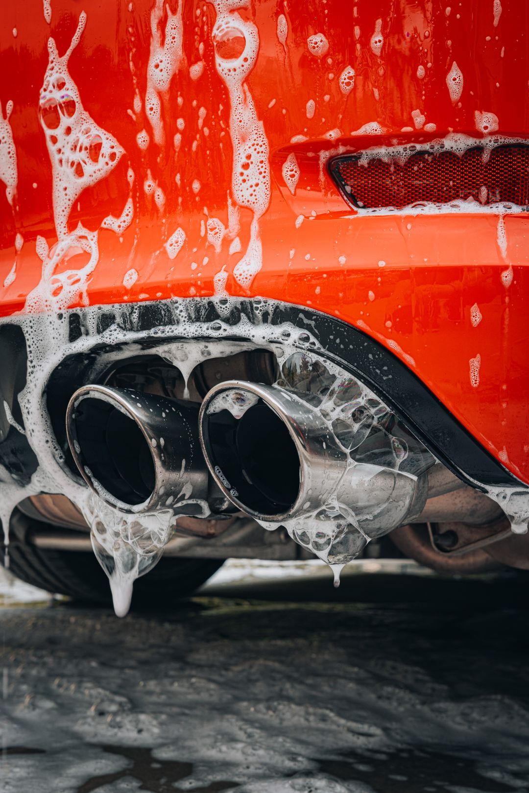 Foam suds on the rear of a red car during a Platinum Wash