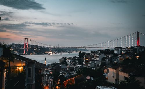 Free Bosphorus Bridge illuminated at dusk over Istanbul's urban landscape with a tranquil evening sky. Stock Photo