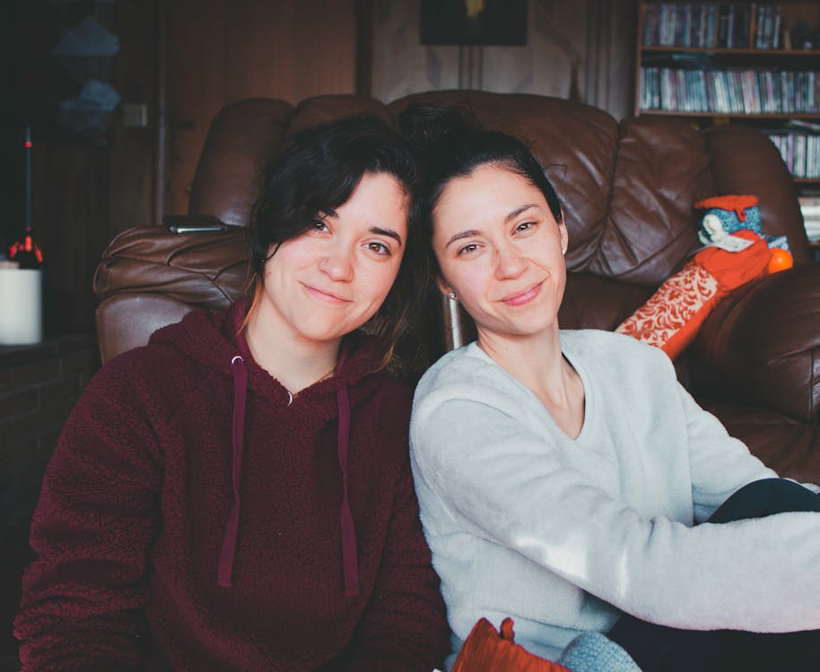 Two Women Sitting On The Floor Near Sofa 