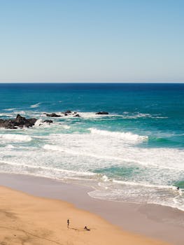 A tranquil beach with gentle waves and a clear sky, perfect for a relaxing getaway.
