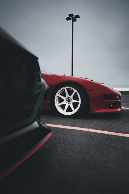 Free Close-up shot of a sleek red sports car parked on urban asphalt Stock Photo