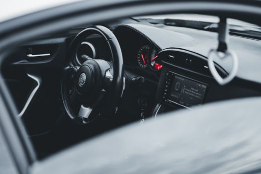 Close-up of a sleek modern car interior featuring a stylish steering wheel and dashboard controls.