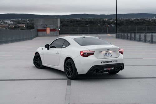 Free A sleek white Toyota sports car customized and parked in an urban rooftop parking lot. Stock Photo