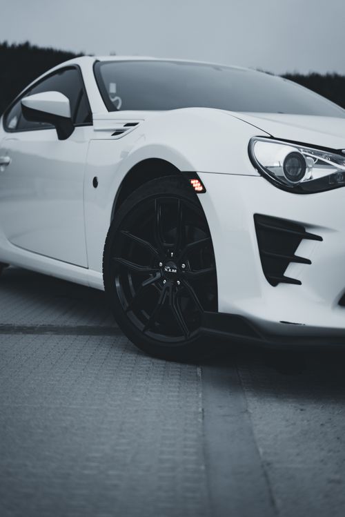 Free Detailed view of a white sports car emphasizing black wheels and sleek design on an overcast day. Stock Photo