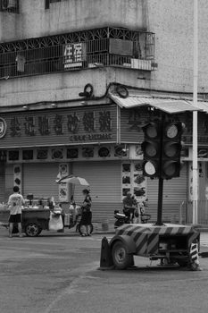 Black and white photo of a city street with a food stand and people.