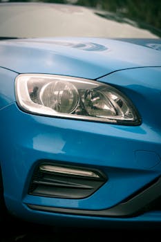 Detailed shot of a blue car's headlight and bumper with sleek design.
