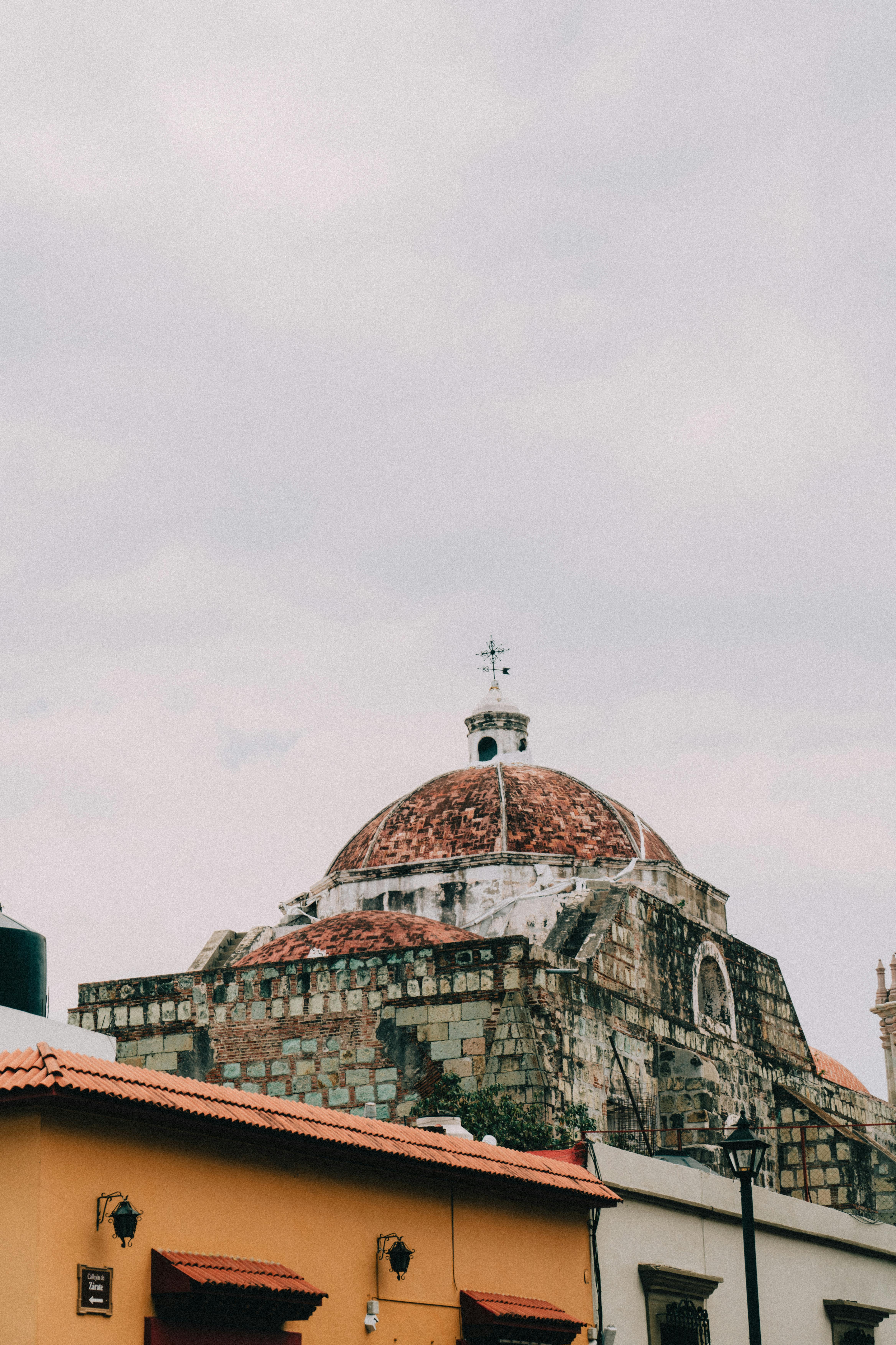 Low angle view of a historic stone church dome, showcasing intricate details with a cloudy sky backdrop.