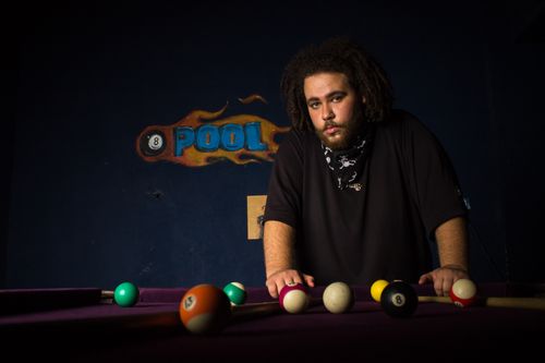 Free A man stands by a pool table, ready to play a game in a dimly lit room. Stock Photo