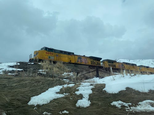 Clouds over Train with Yellow Wagons in Snow