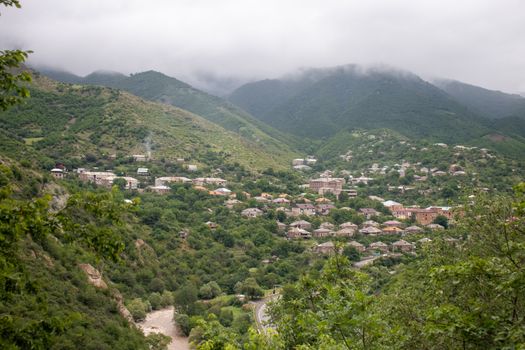 Charming hillside village surrounded by lush green forests and misty mountains.