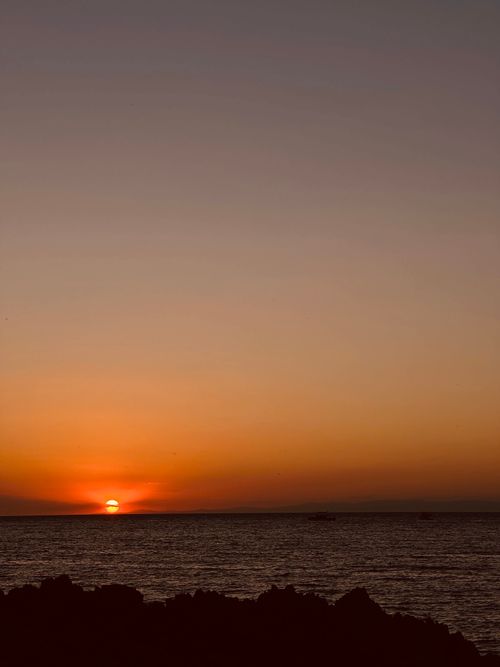 Free Serene sunset casting warm hues over a calm ocean horizon, creating a peaceful atmosphere. Stock Photo
