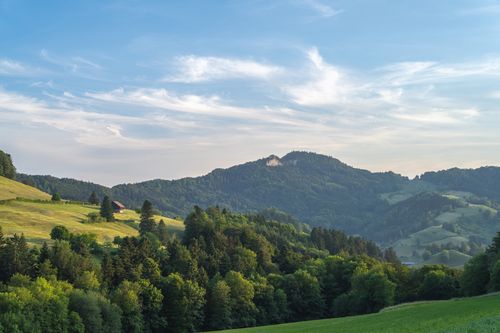 Free Beautiful landscape featuring rolling hills, a farmhouse, and lush greenery beneath a clear sky. Stock Photo
