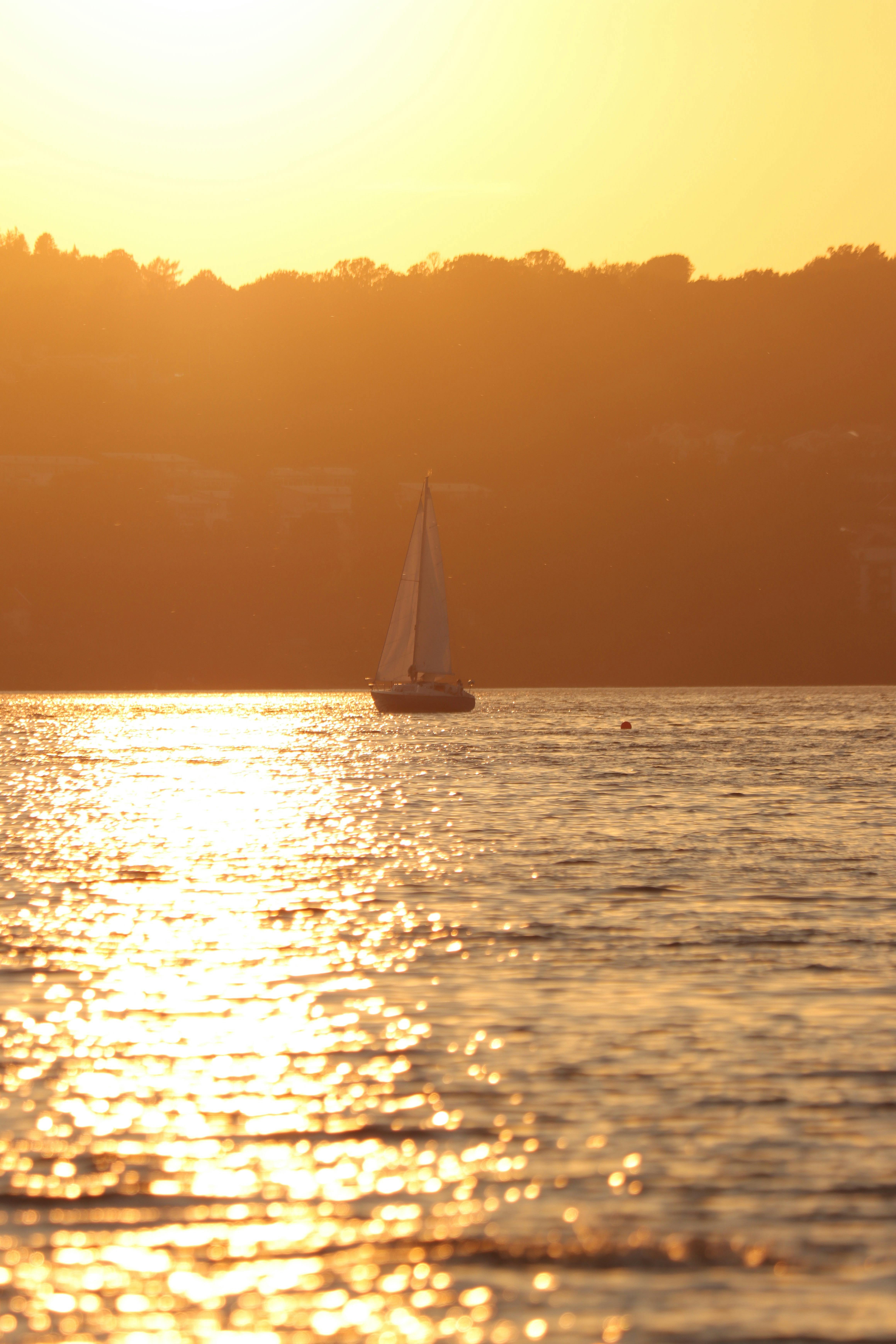 Sailboat gliding on Lake Vättern during a vibrant sunset in Jönköping, Sweden.