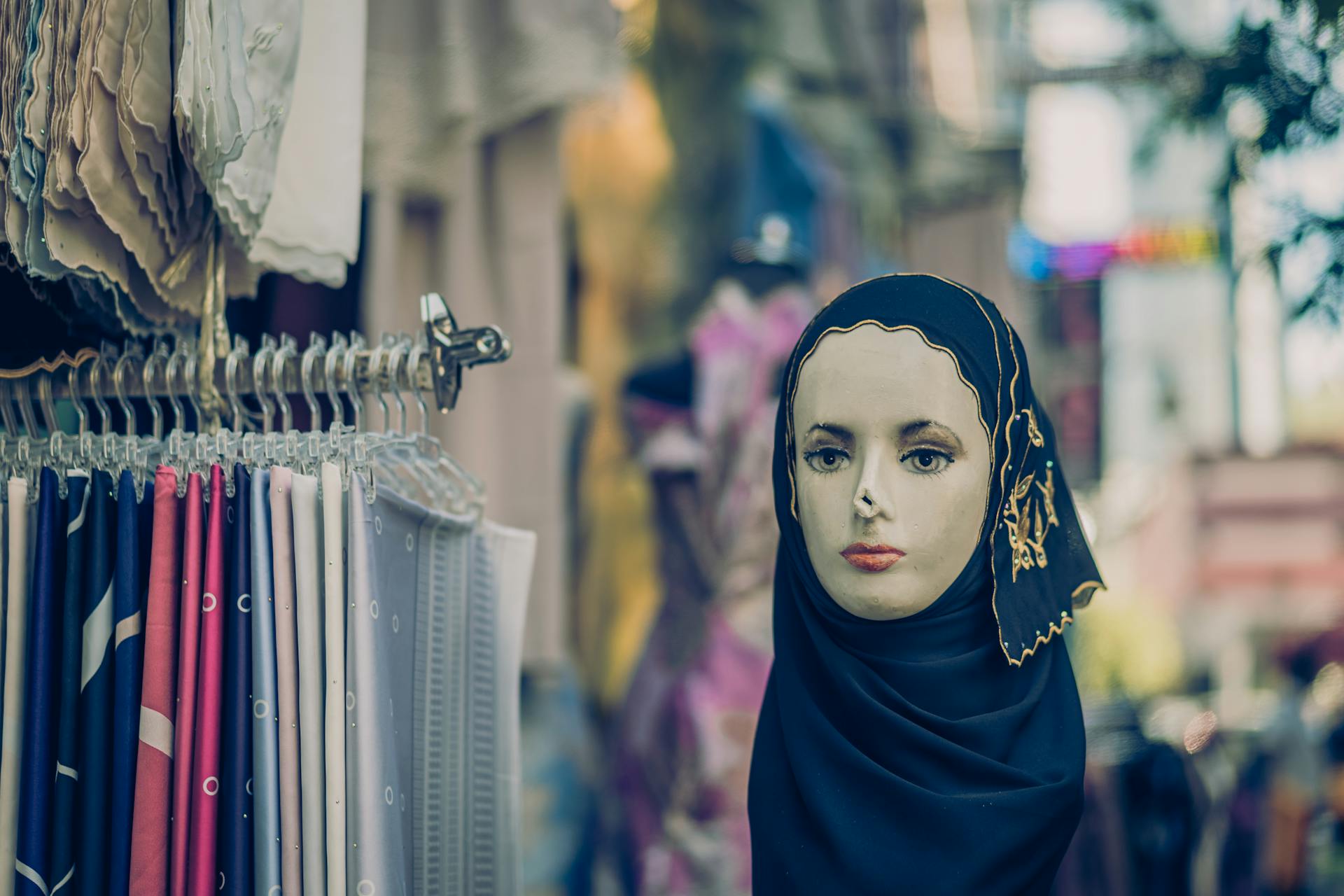 Colorful hijabs displayed on a mannequin in a Kuala Lumpur street market.