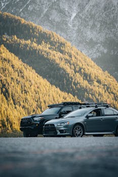Two cars parked in a sunlit mountain setting, highlighting adventure and outdoor travel.