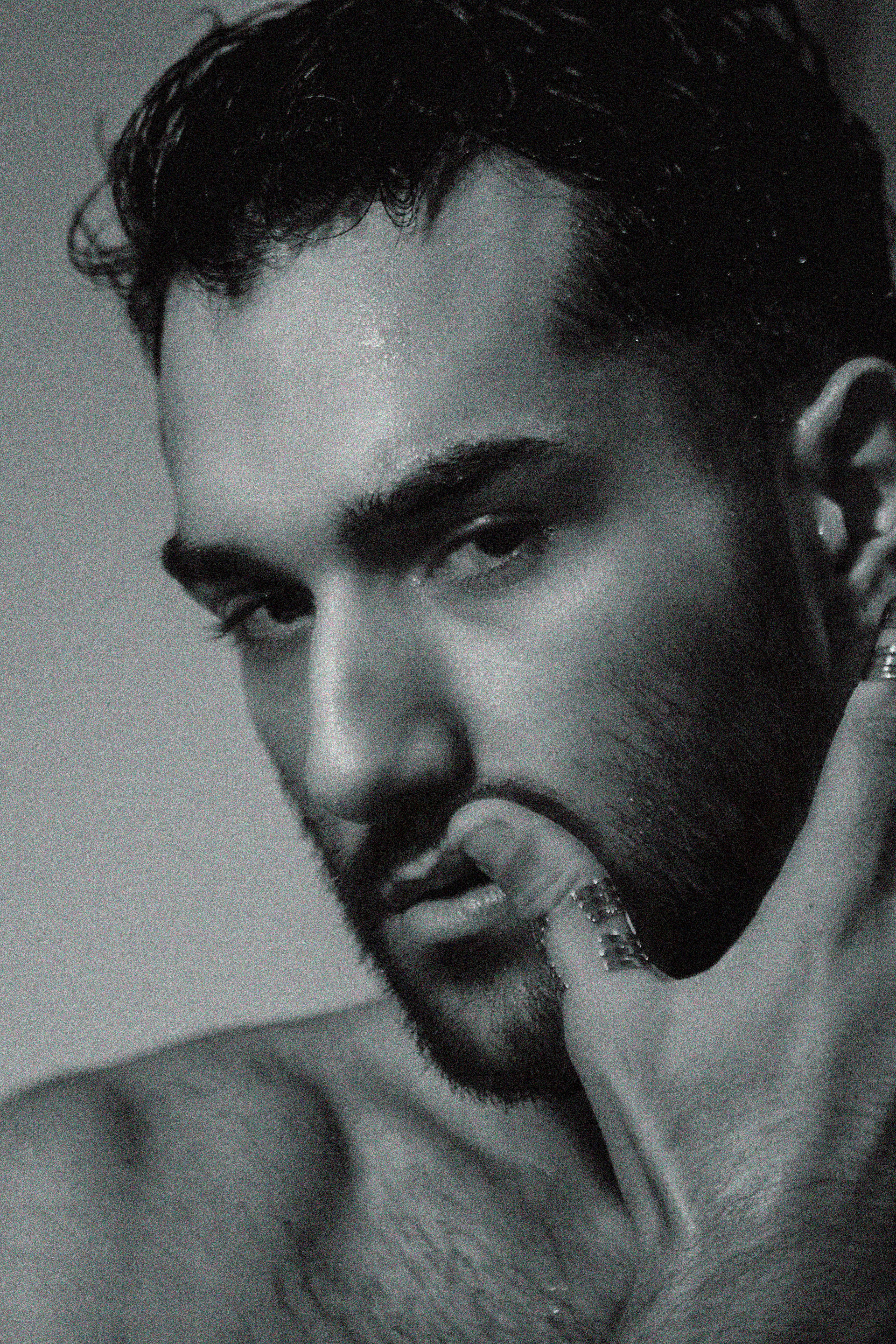 Intense black and white portrait of a pensive man with a beard and unshaven look.
