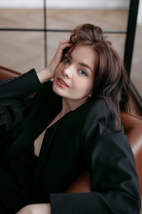 Young Brunette Woman in Black Jacket Sitting on Sofa