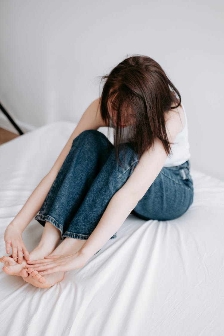 Sitting Woman On Bed Touching Her Toes