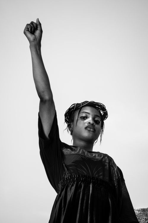 Free Black and white portrait of a woman raising her fist, symbolizing empowerment and strength. Stock Photo