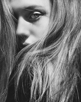 Dramatic black and white close-up portrait showcasing a woman's face with striking eye detail.