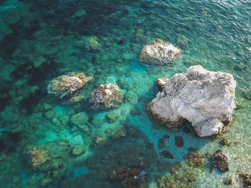 Free Stunning aerial shot of a rocky coastal seabed with vibrant blue water. Stock Photo