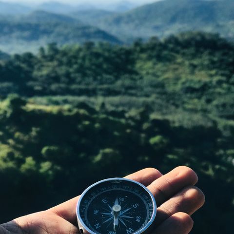Hand holding a compass over a valley — structure and coaching