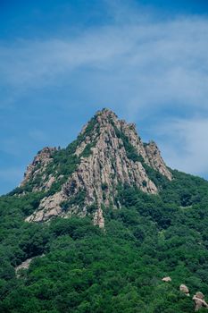 Stunning mountain peak with dense greenery under a clear blue sky.
