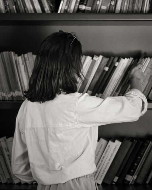 Free A woman choosing books in a library in a monochrome setting. Stock Photo