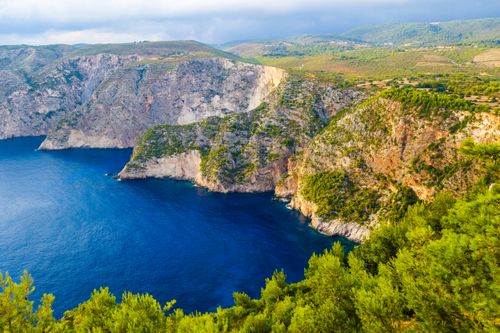 Free A breathtaking aerial view of coastal cliffs meeting the deep blue sea under a vibrant sky. Stock Photo