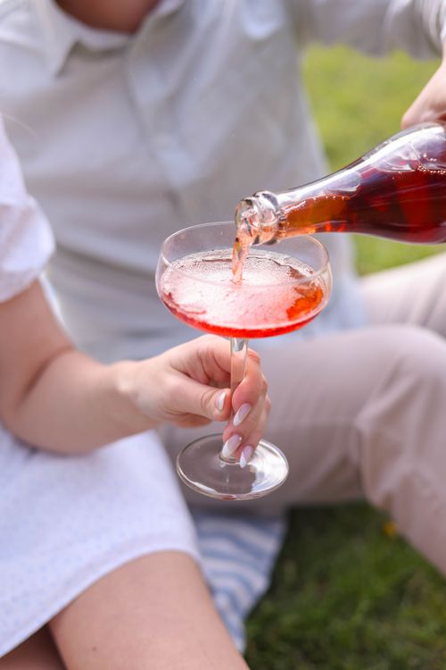 Free A vibrant outdoor picnic with rosé wine being poured into a glass. Perfect for summer stock imagery. Stock Photo