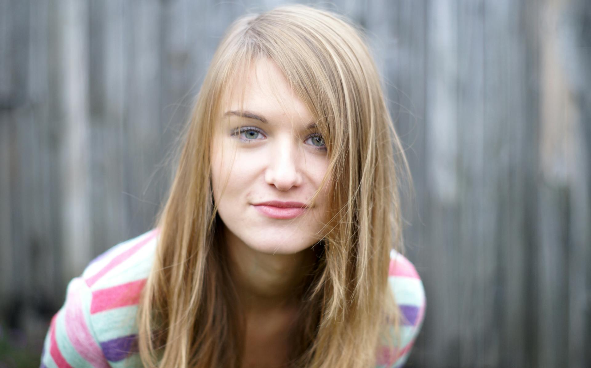 Une jeune femme aux longs cheveux blonds pose pour un portrait.