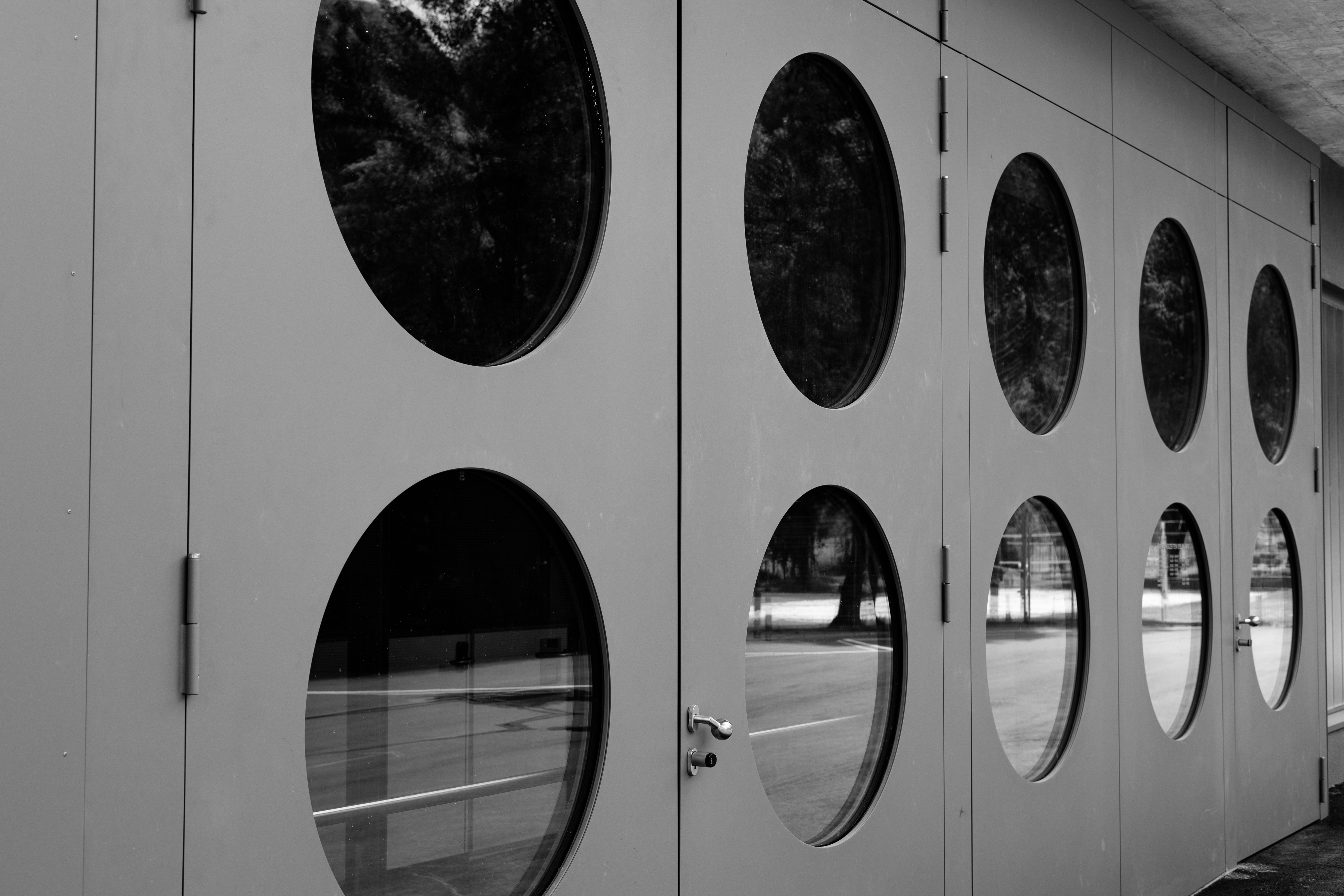 Black and white image highlighting a modern facade with circular windows and a minimalist design.