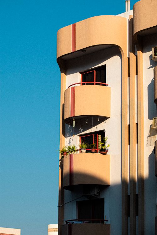 Free Sunlit residential building in Dubai with distinctive balconies, casting strong shadows. Urban architecture captured during daytime. Stock Photo