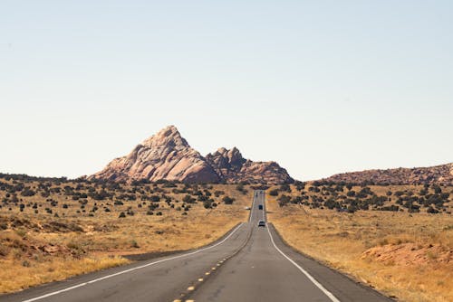 Symmetrical View of an Asphalt Road in a Desert with Mountains in Distance 