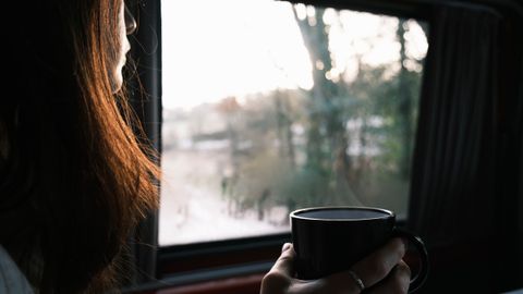 A serene moment captured as a woman savors her coffee by the window, soaking in the morning light.